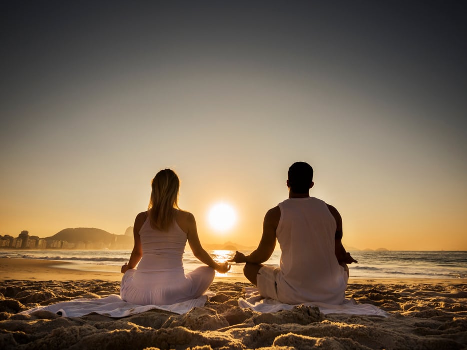 Couple meditating at sunset.